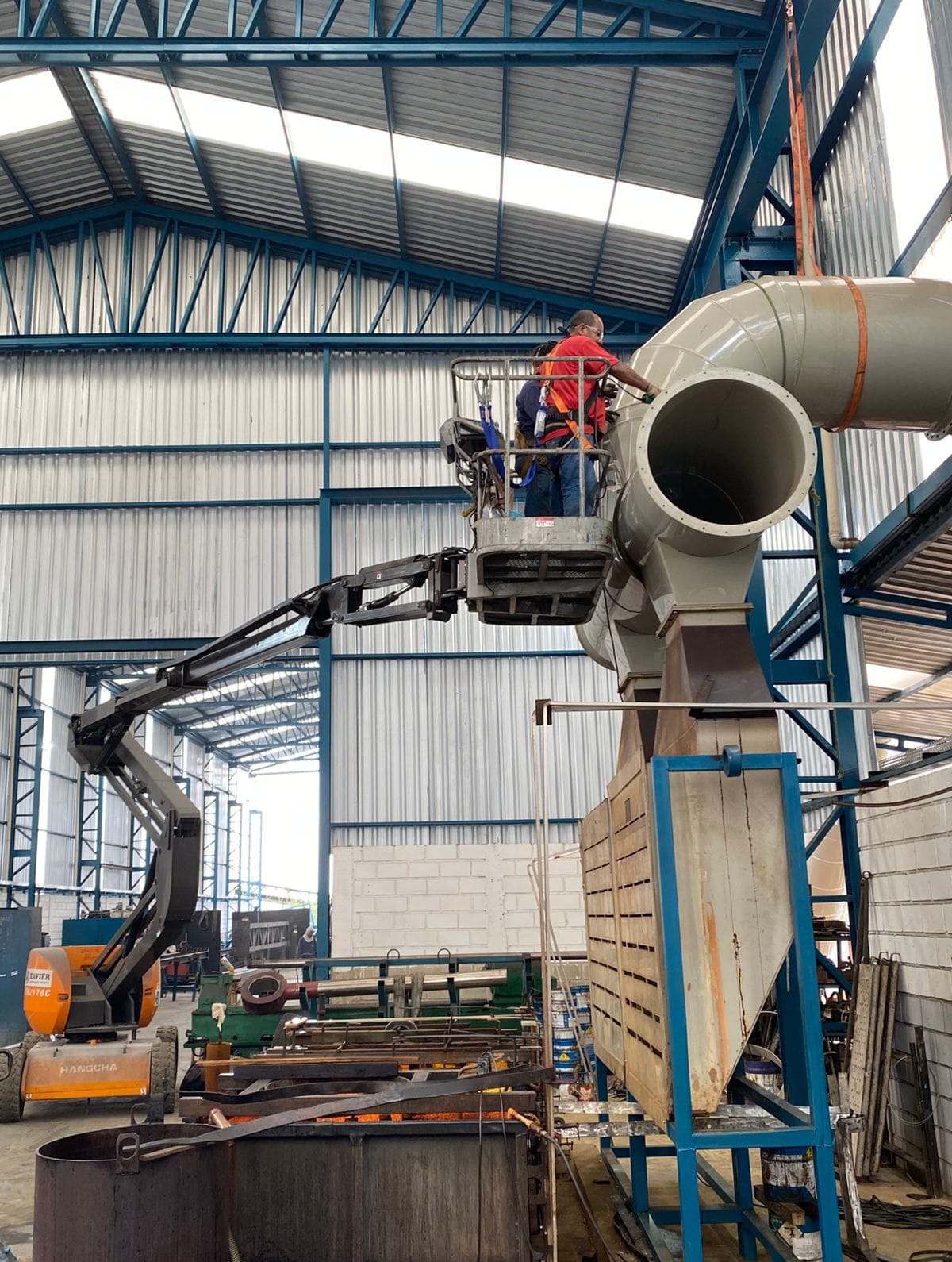 Técnicos instalando sistema de exaustão de grande porte em galpão industrial